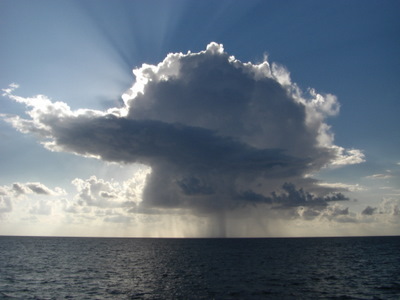 Small Ocean Rain Cloud with Sun Rays Behind.